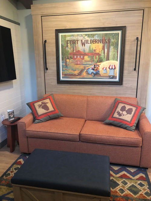 The living and dining area features a sofa in front of a Murphy-style queen bed hidden in the wall. The living and dining area features a sofa in front of a Murphy-style queen bed hidden in the wall.